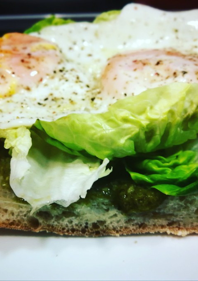 Una foto de Huevos fritos sobre chapata bañada en salsa pesto