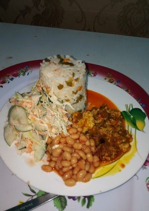 A picture of Buttered Veggie Rice, Palm oil egg sauce,baked beans and salad.