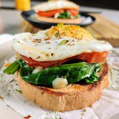 A picture of Sunny side up eggs with garlic spinach and roasted tomato.
