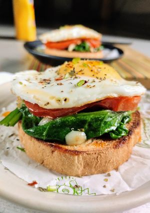 A picture of Sunny side up eggs with garlic spinach and roasted tomato.