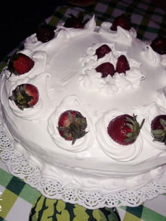 Una foto de Torta decorada con crema italiana y frutillas