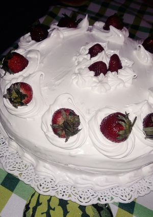 Una foto de Torta decorada con crema italiana y frutillas