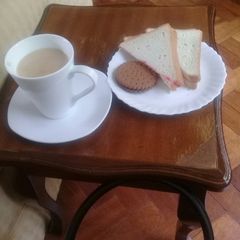 A picture of Cup of tea, slice of buttered n jam bread n a chocolate cookie.