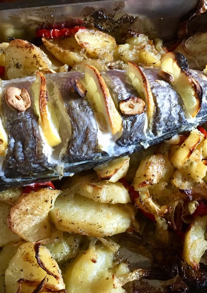 Una foto de Cola de merluza con patatas pimientos rojos y cebolla cebolla