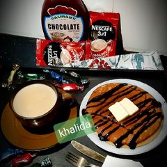 Banana pancakes chocotopping with coffee A picture of Banana pancakes chocotopping with coffee.