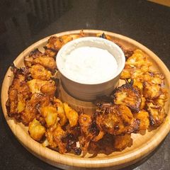A picture of Buffalo cauliflower wings with blue cheese dip.
