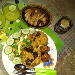 A picture of Jollof rice and beans with ginger and cucumber drink.
