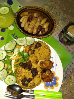 A picture of Jollof rice and beans with ginger and cucumber drink.
