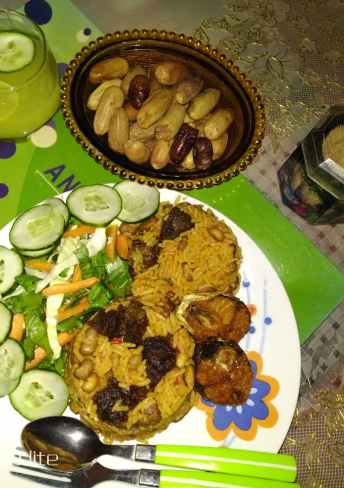A picture of Jollof rice and beans with ginger and cucumber drink.