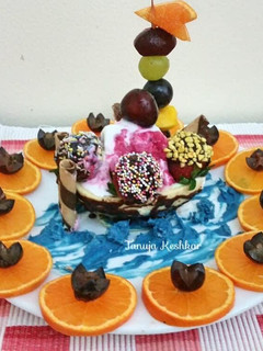 A picture of Chocolate boat with mixed fruit ice cream and chocolate dry fruits balls.