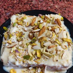 A picture of Bread sponge wrapped with rabdi and nuts sauce.