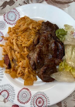 Une photo de Pâtes avec pommes de terre accompagnées d’une côtelette au barbecue et sa salade