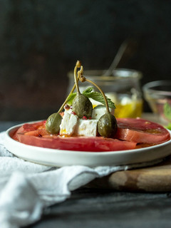 Una foto de Carpaccio de tomate, queso feta y alcaparrones