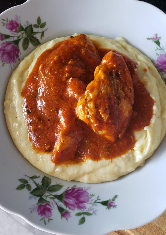 Una foto de Polenta con pechuga en salsa roja
