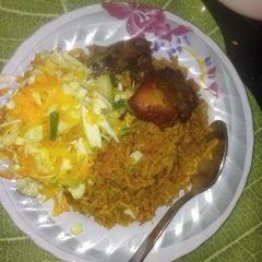 A picture of Jollof rice with fried chicken and salad with heinz salad cream and sprinkled sugar.