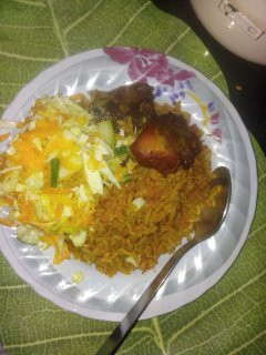 A picture of Jollof rice with fried chicken and salad with heinz salad cream and sprinkled sugar.