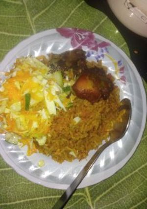 A picture of Jollof rice with fried chicken and salad with heinz salad cream and sprinkled sugar.