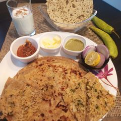 A picture of Punjabi paratha thali(radish layered paratha, Yoghurt lassi).