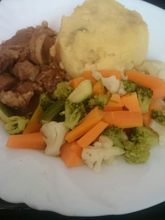 A picture of Mashed potatoes served with beef and greens.