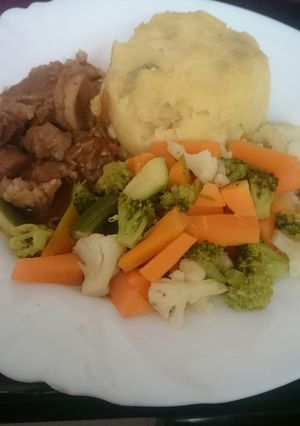 A picture of Mashed potatoes served with beef and greens.