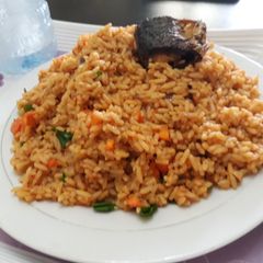 A picture of Jollof rice with carrots and green peas with fish.