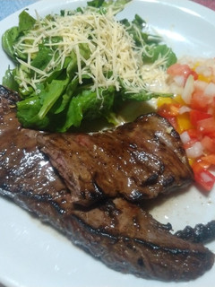 Una foto de Entraña con salsa criolla y ensalada de rúcula