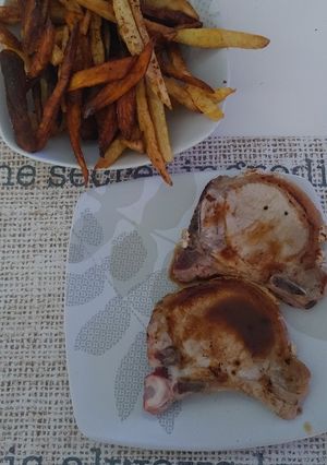 Una foto de Costillitas de cerdo con papas y batata frita