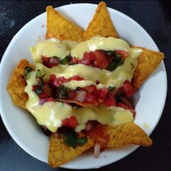A picture of Nachos with Salsa sauce and cheese dip.