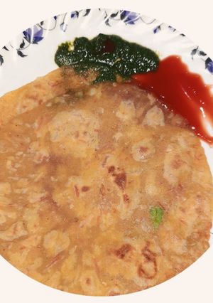 A picture of Spicy vej paratha with red and green chutney.