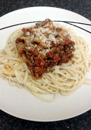A picture of spaghetti bolognaise & garlic baguette.