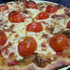 A picture of Vegetarian pizza with roasted peppers and cherry tomatoes.
