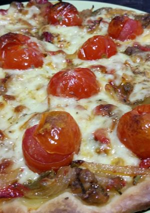 A picture of Vegetarian pizza with roasted peppers and cherry tomatoes.