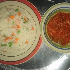 A picture of White rice with carrots and green peas with tomato sauce.
