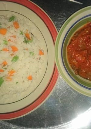 A picture of White rice with carrots and green peas with tomato sauce.