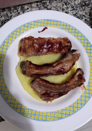 Una foto de Costillas asadas a la barbacoa sobre cama de puré de patata