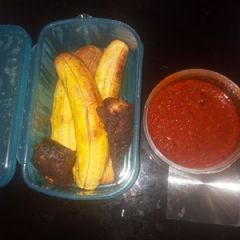 A picture of Roasted plantain with fish and palmoil sauce.