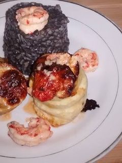 Una foto de Roll de pez gallo con risotto negro y gambas al ajillo