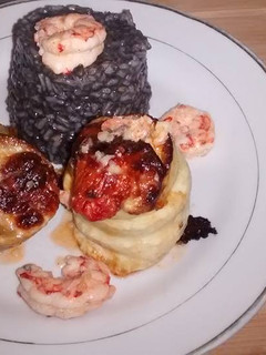 Una foto de Roll de pez gallo con risotto negro y gambas al ajillo