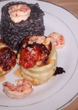 Una foto de Roll de pez gallo con risotto negro y gambas al ajillo