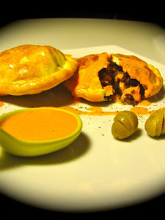 Una foto de Empanadillas de morcilla y pera con salsa de piquillos