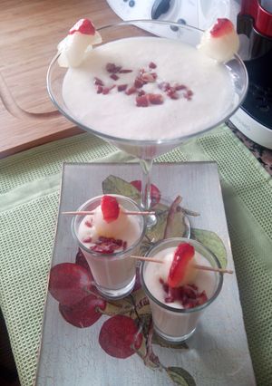 Una foto de Copa o chupito de crema de melón con jamón, bola de melón y pétalo de fresa