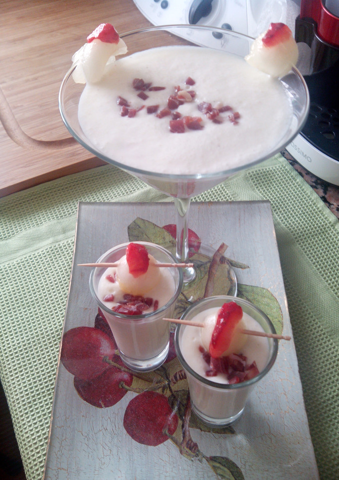 Una foto de Copa o chupito de crema de melón con jamón, bola de melón y pétalo de fresa
