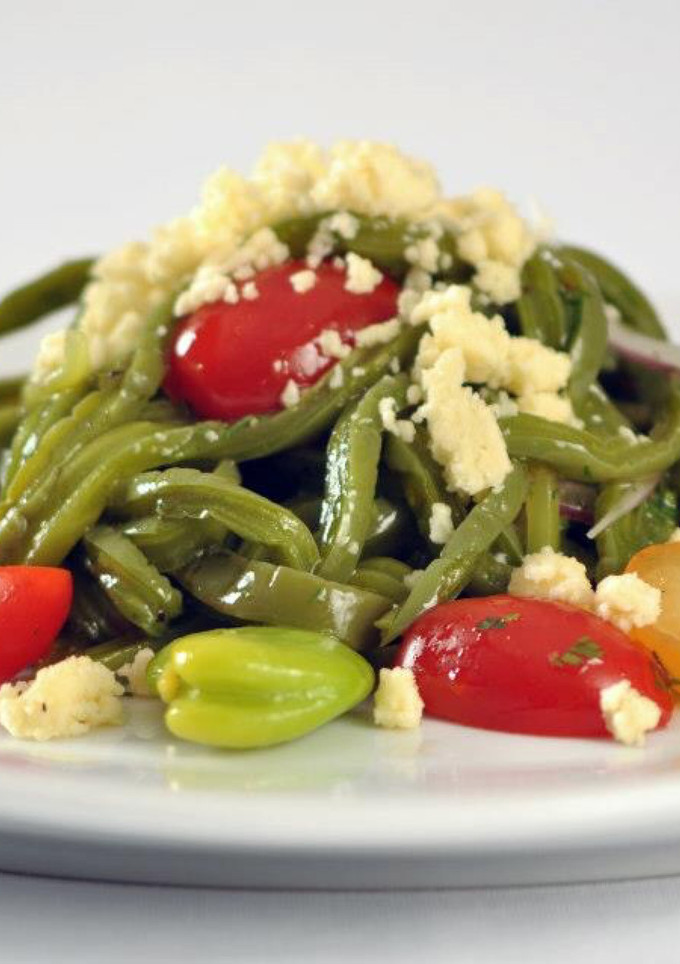 Una foto de Ensalada de nopales, habas y tomates con queso fresco.