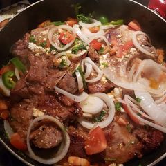 A picture of Pork chops with tomatoes and onions and jalapenos.