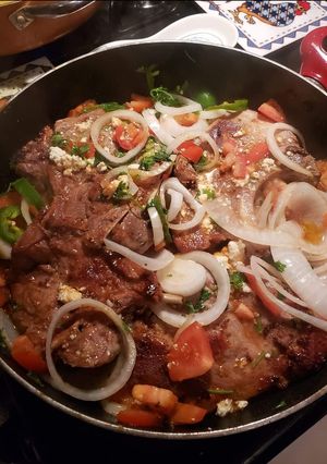 A picture of Pork chops with tomatoes and onions and jalapenos.