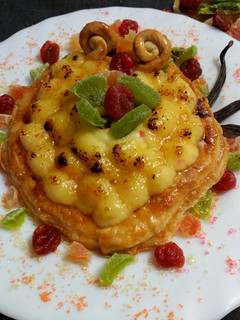 Una foto de Tartaleta de crema de yema y vainilla ,con azucar quemada y fruta confitada.