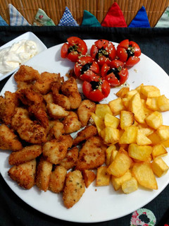 Una foto de Delicias de pollo con rebozado crujiente , patatas y cherry.