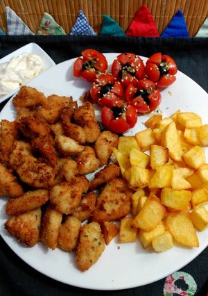 Una foto de Delicias de pollo con rebozado crujiente , patatas y cherry.