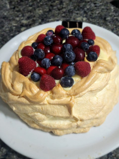 Una foto de Pavlova rellena de crema pastelera con frutos del bosque