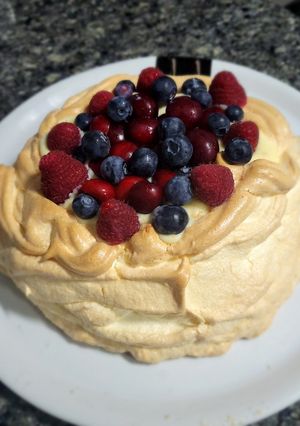 Una foto de Pavlova rellena de crema pastelera con frutos del bosque